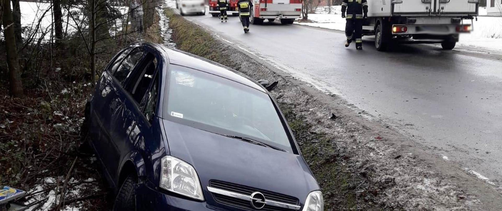 Samochód osobowy w rowie a na drodze samochód dostawczy. W tle widać samochody pożarnicze.
