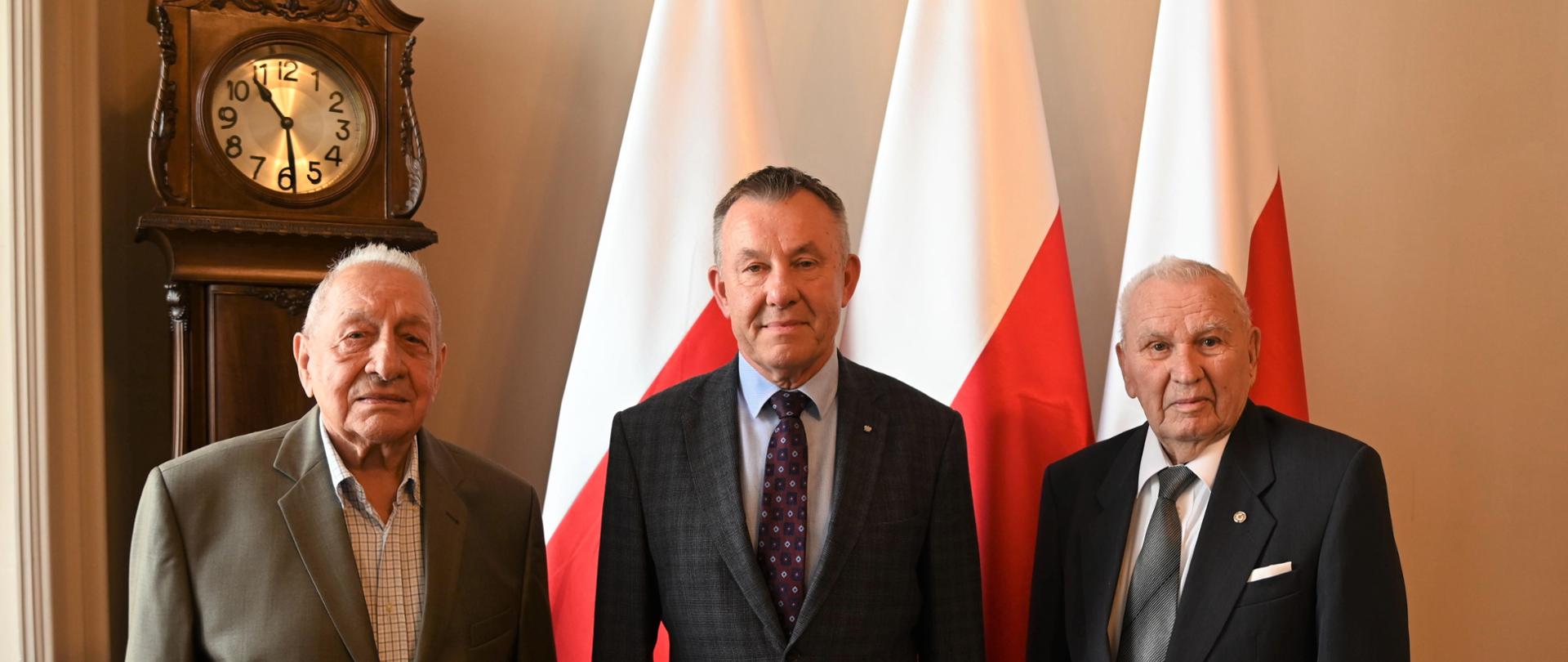 Wojewoda łódzki Karol Młynarczyk z przedstawicielami Rady Kombatanckiej na tle biało czerwonych flag