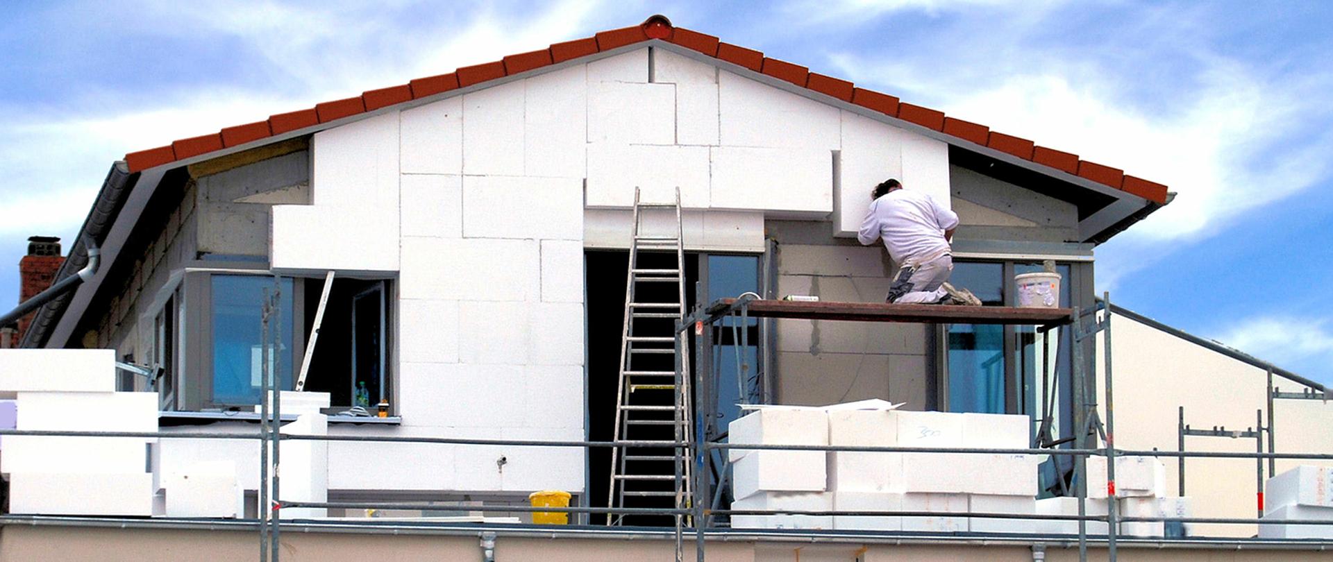 Worker mounting new thermal insulation on house walls