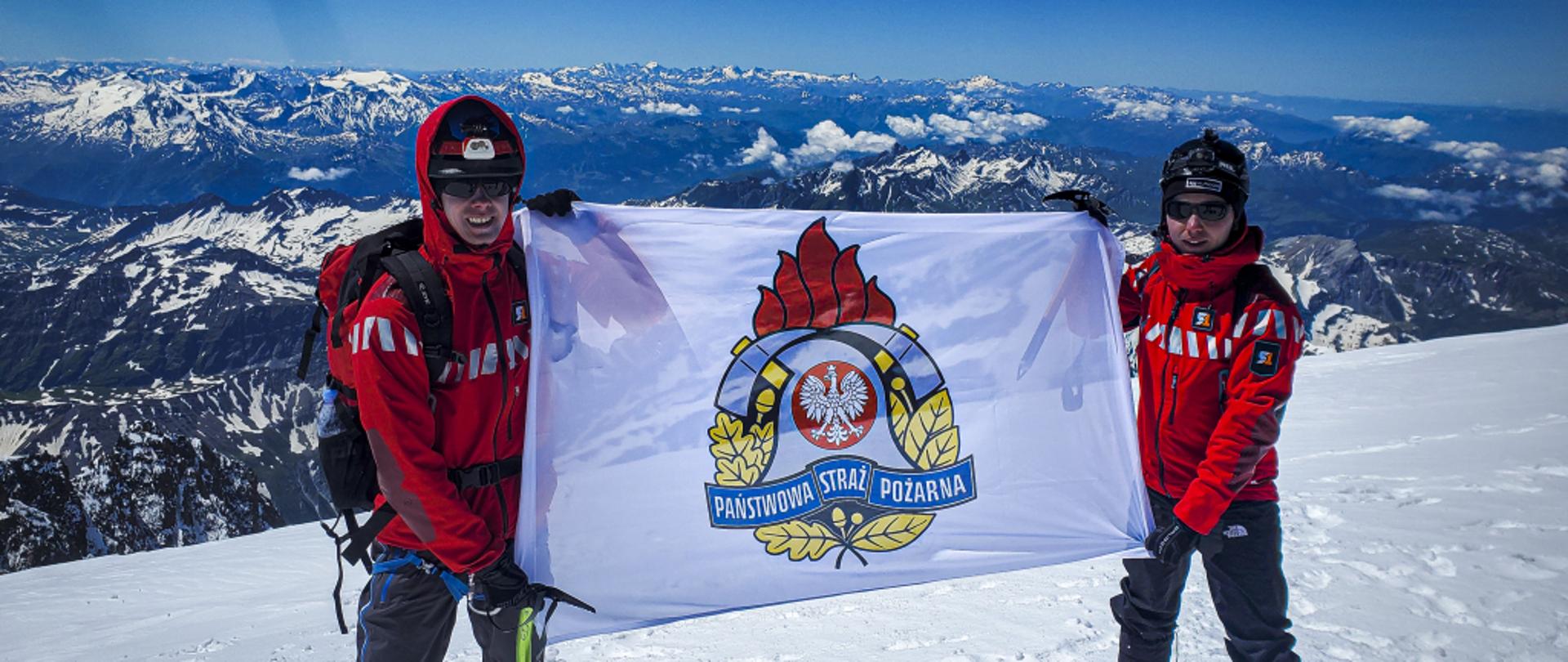 strażacy z flagą PSP na szczycie