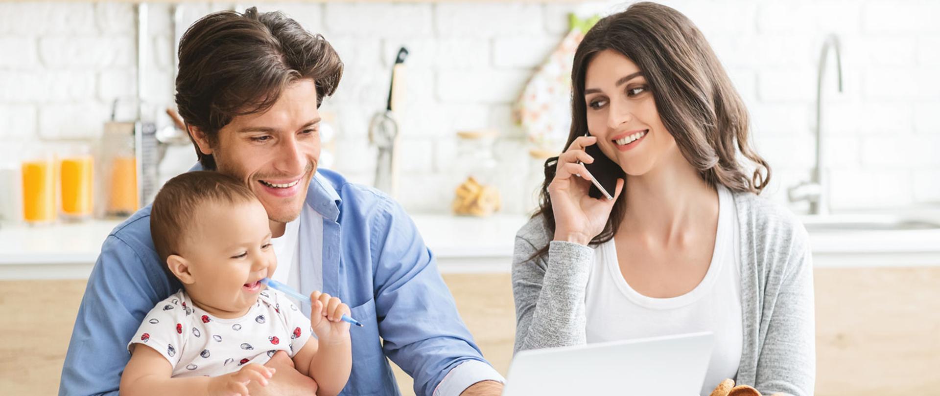 Zdjęcie przedstawia rodziców z małym dzieckiem siedzących przed komputerem