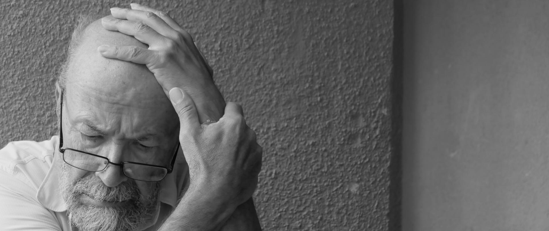 mężczyzna senior trzyma się za głowę