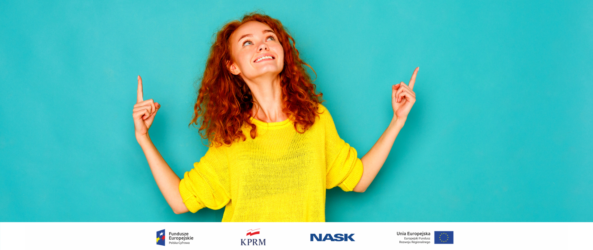 Rudowłosa kobieta w żółtym swetrze na zielono-niebieskim tle. Patrzy w górę, pokazuje tam także palcami wskazującymi obu dłoni.