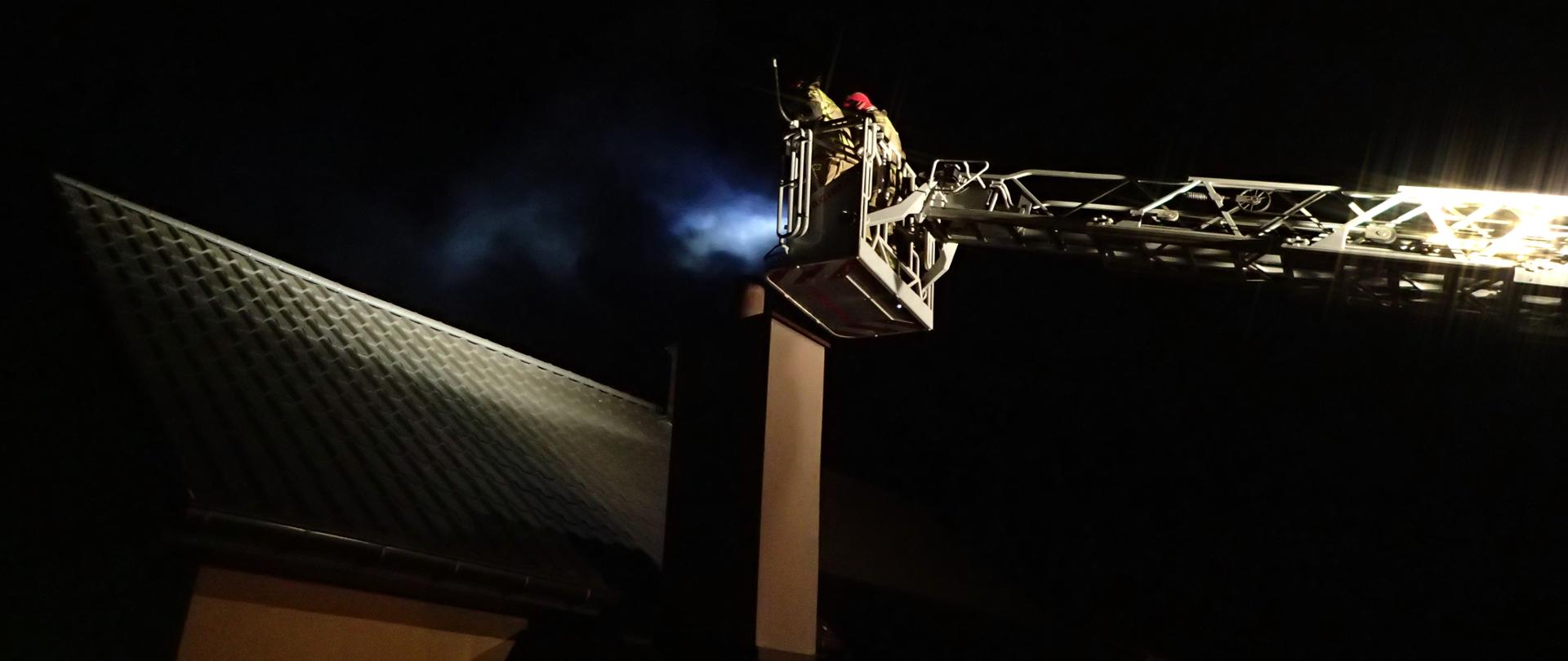 Strażacy w koszu drabiny SD-23 gaszący komin budynku mieszkalnego