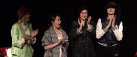 Zdjęcie prezentuje cztery postaci - Słuchaczki Studium przebrane w różne stroje. Osoby na zdjęciu klaszczą po występie na scenie, 