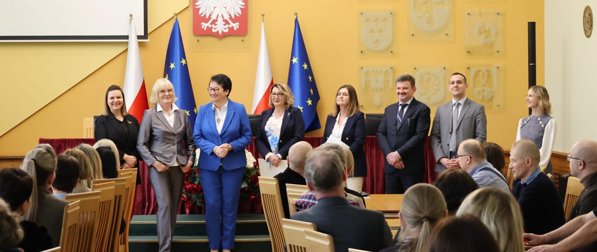 Uroczyste ogłoszenie rozdzielenia dotychczas funkcjonującego wydziału i utworzenie dwóch nowych: Wydziału Zdrowia i Wydziału Polityki Społecznej. Na zdjęciu widać Wojewodę Opolskiego, Po jej lewej stoi Dyrektor Wydziału Zdrowia, Mirosława Kwatek-Hoffmann oraz Dyrektor Generalna Agnieszka Królikowska. Po prawej od Wojewody stoi Dyrektor Wydziału Polityki Społecznej Ewa Pawlinów, Beata Jabłońska Zastępca Dyrektora Wydziału Zdrowia, Wicewojewoda Opolski Piotr Pośpiech, Dyrektor Biura Wojewody Jarosław Draguć oraz Zastępca Dyrektora Biura Wojewody Agnieszka Konopacka. 