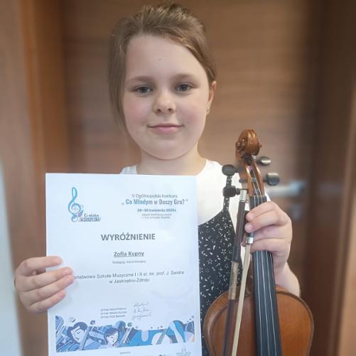 Zosia Kupny trzymająca w rękach dyplom z konkursu i skrzypce