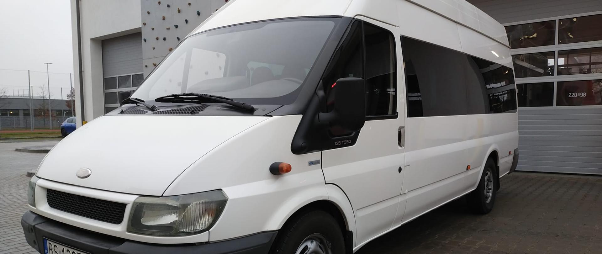 Biały autobus na tle bram garażowych