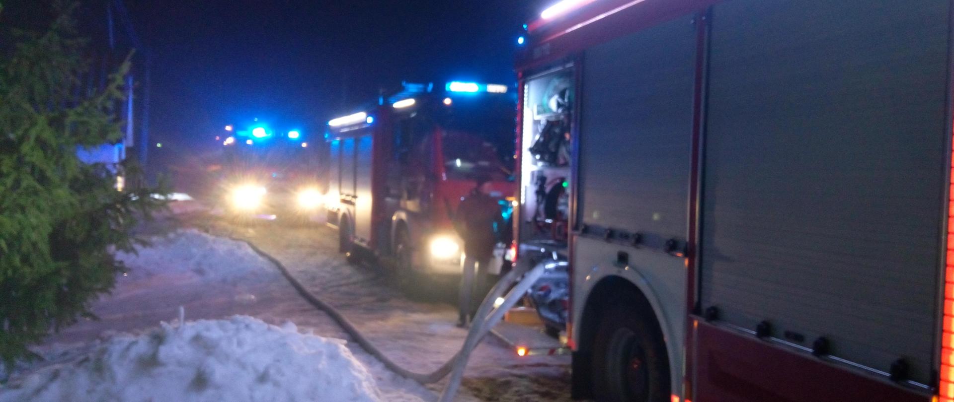 Na zdjęciu widać samochody pożarnicze oraz rozwinięte linie gaśnicze.