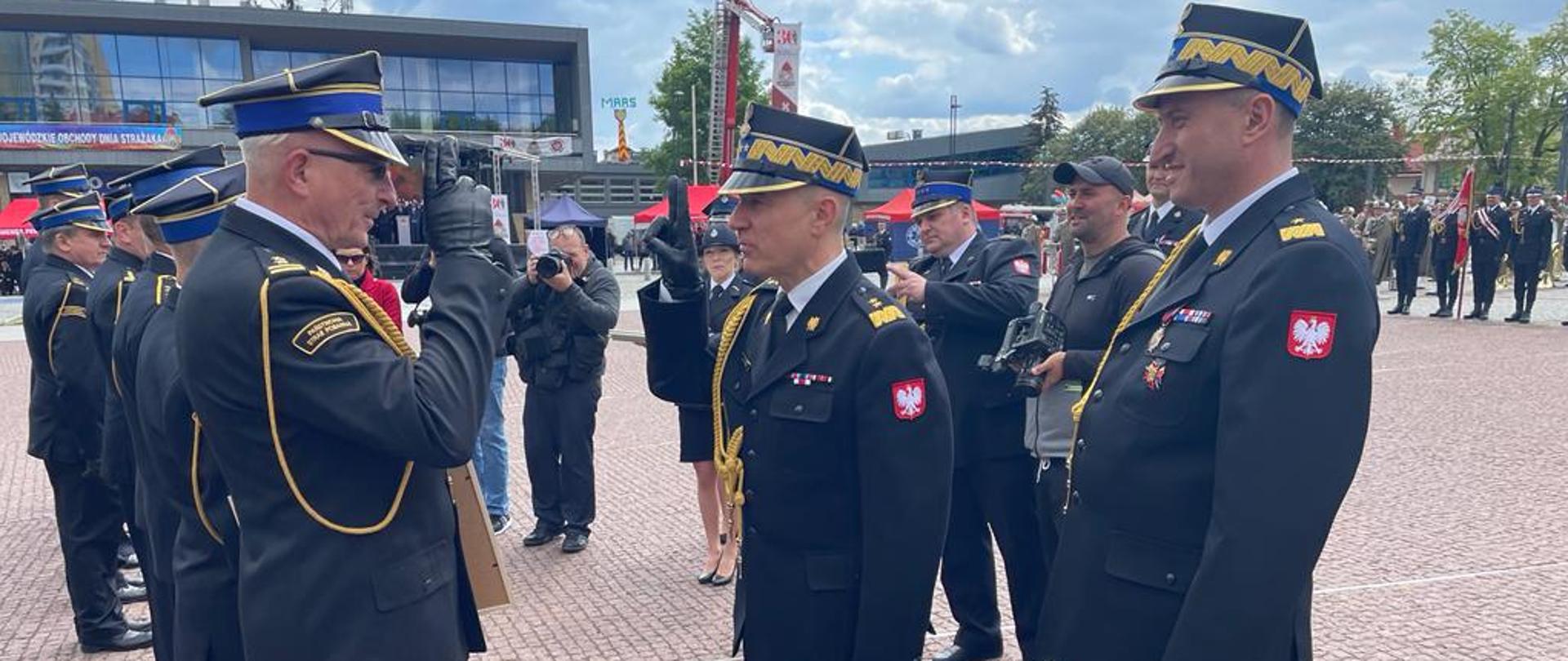Na zdjęciu widać jak komendant główny wręcza awanse na wyższe stopnie strażakom PSP razem z wojewódzkim komendantem PSP 