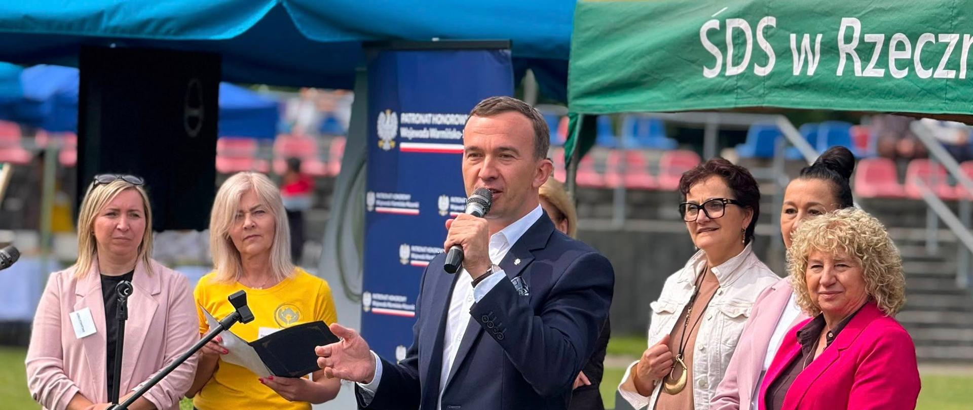 Mężczyzna w garniturze przemawia prze mikrofon 