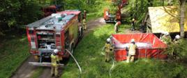 Zdjęcie przedstawia bufor wodny wykonany z przenośnego zbiornika brezentowego oraz zasilające go w wodę pojazdy i pracujących na miejscu strażaków.