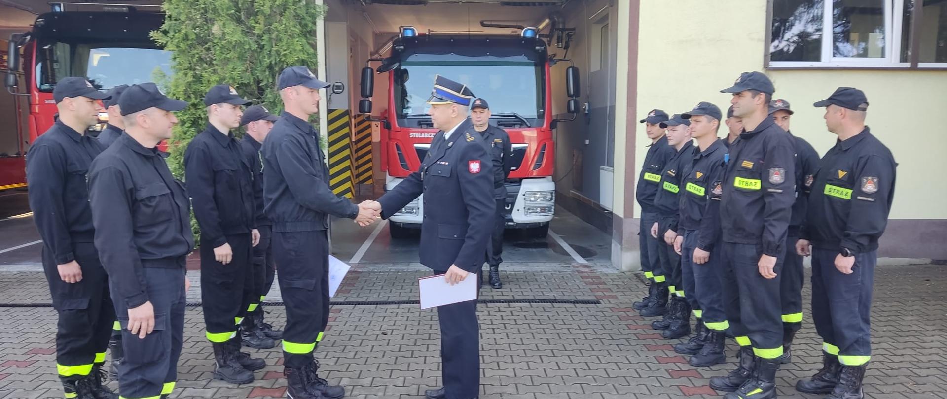 NA zdjęciu widać komendanta podczas zmiany służbowej wręczającego decyzję o przyznaniu nagrody KG 