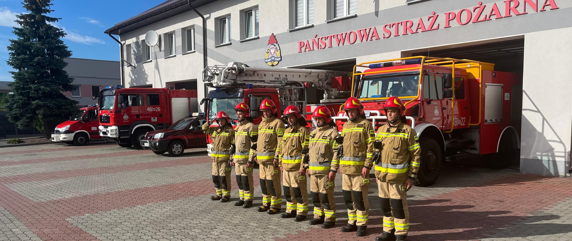 Zdjęcie przedstawia strażaków w zbiórce przed budynkiem komendy powiatowej PSP w Lubaczowie.
