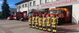 Zdjęcie przedstawia strażaków w zbiórce przed budynkiem komendy powiatowej PSP w Lubaczowie.