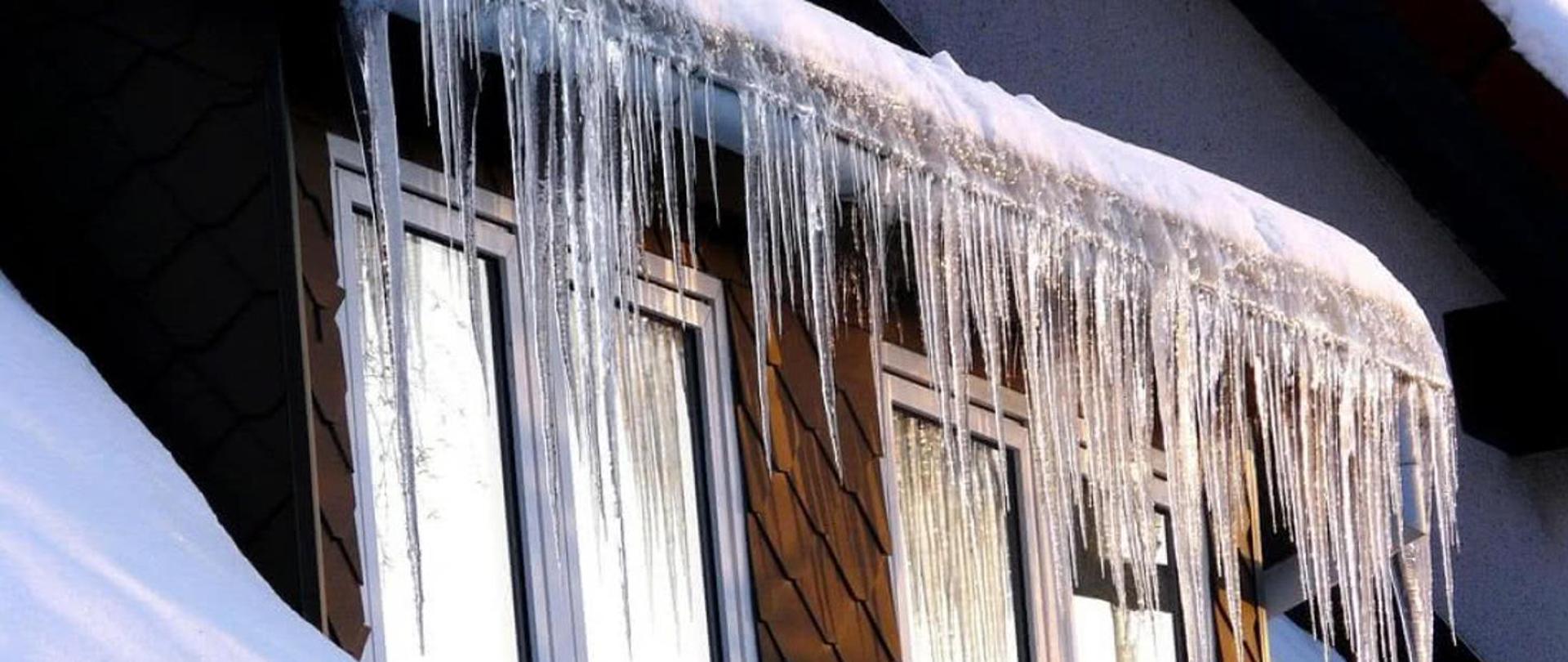 Obrazek przedstawiający zwisające sople z dachu domu