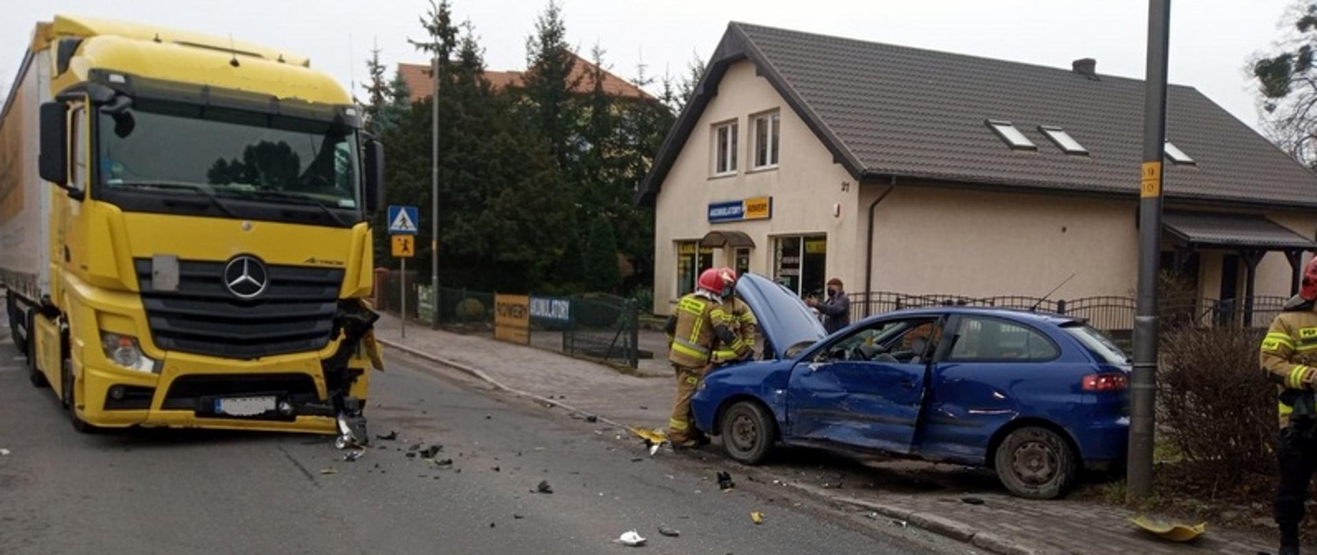 na zdjęciu widać dwa samochody, które uczestniczyły w wypadku. Po lewej przód żółtego samochodu ciężarowego, po prawej zniszczony niebieski samochód osobowy.