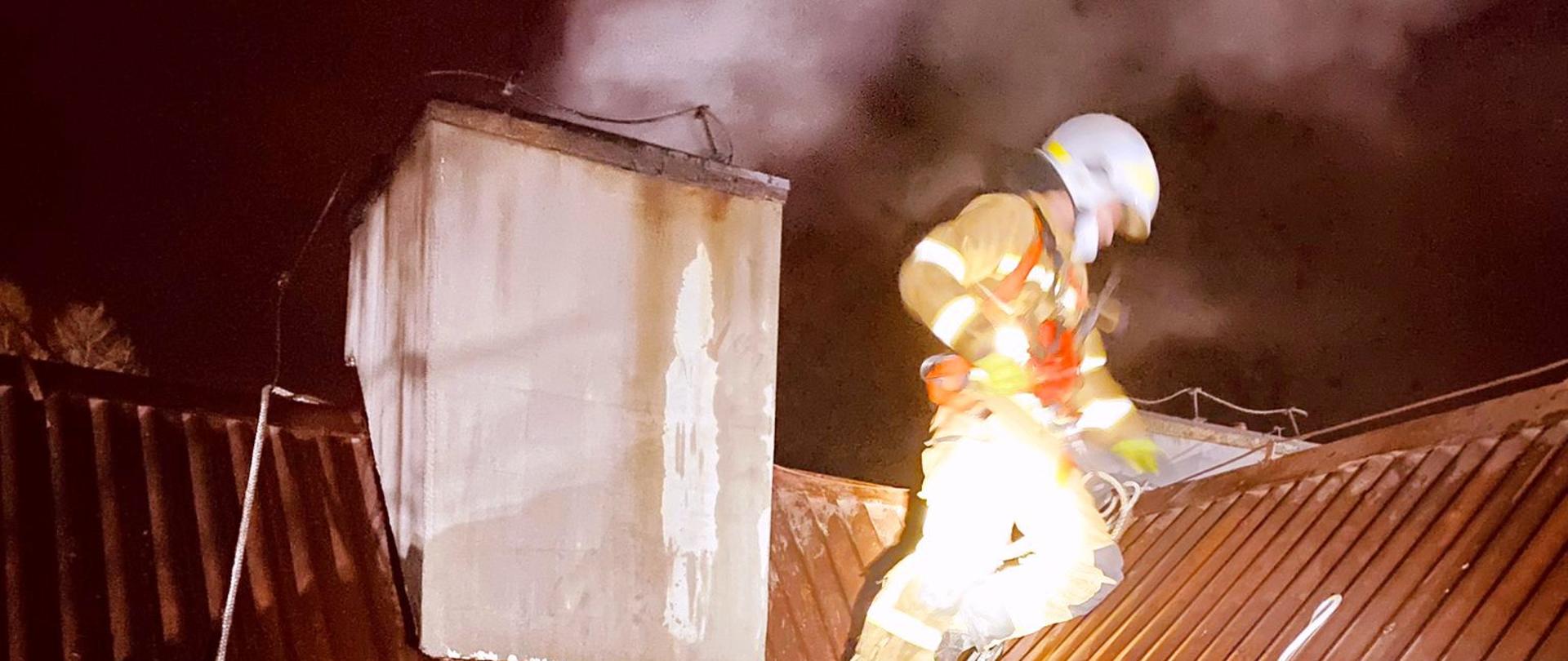 Strażak na dachu prowadzi działania