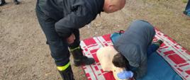 Na zdjęciu strażak uczy pierwszej pomocy mężczyznę