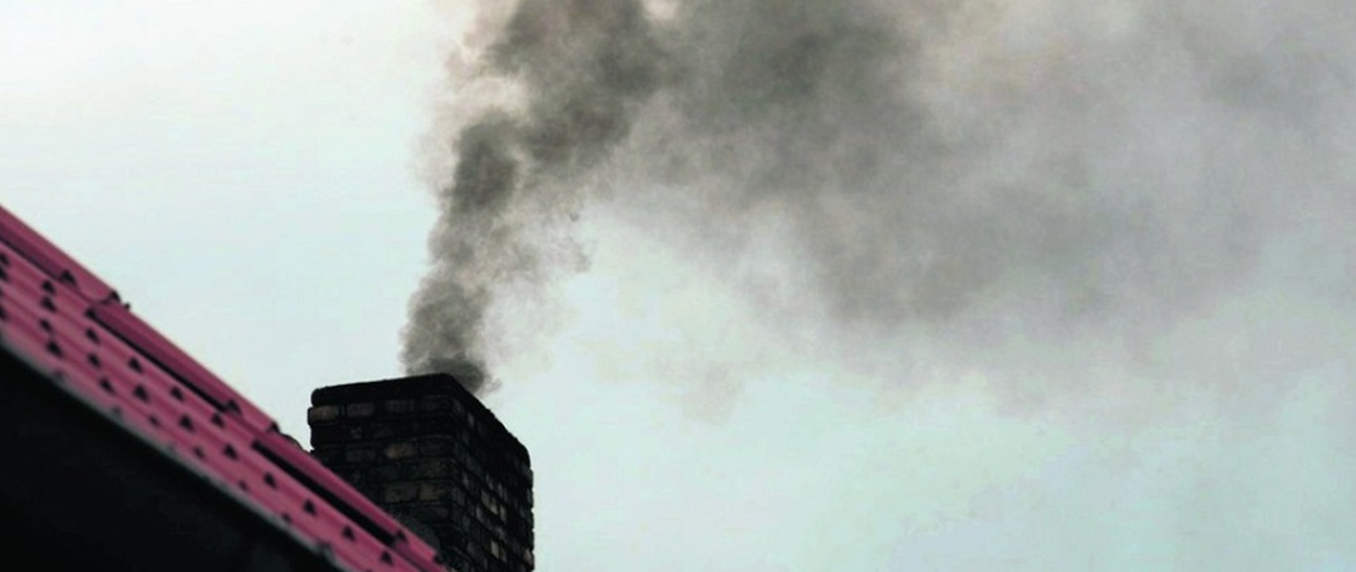 Zdjęcie przedstawia dym unoszący się z komina na tle nieba