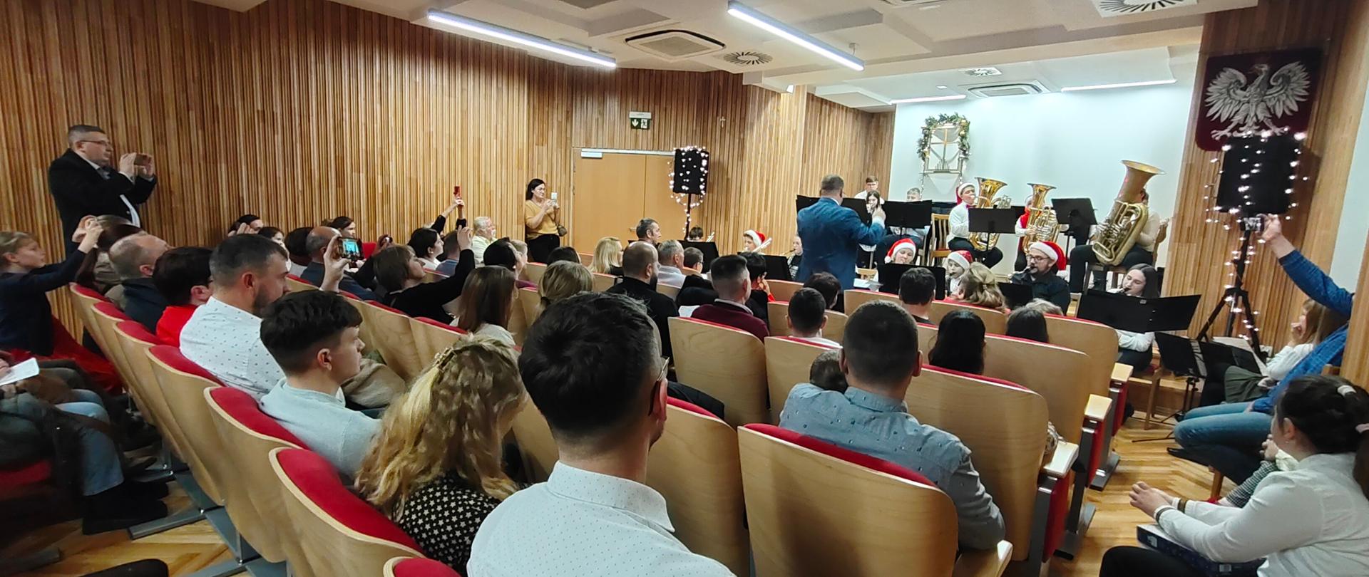 Zdjęcie przedstawia widok na salę koncertową podczas występu na scenie szkolnego Big Bandu