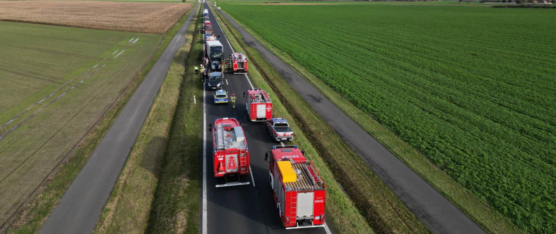 Wypadek z lotu ptaka. Na jezdni stoją wozy strażackie oraz samochody biorące udział w wypadku. Obok nich chodzą strażacy oraz osoby postronne.