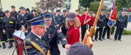 Komendant Powiatowy PSP w Pucku przybija symboliczną tabliczkę z okazji 20-lecia Młodzieżowej Drużyny Pożarniczej w Mieroszynie. Komendant jest ubrany w mundur galowy. 