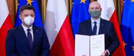 Michał Dworczyk, obok stoi Zbigniew Hoffmann z aktem nominacji.