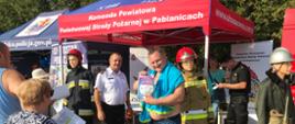Na stoisku KP PSP w Pabianicach komendant powiatowy wręcza zwycięzcom konkursu dualne czujki tlenku węgla i dymu.