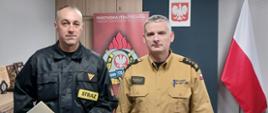 Komendant Powiatowy Państwowej Straży Pożarnej w Człuchowie st. bryg. Radosław Batruch stoi w gabinecie i wręcza akt mianowania st. ogn. Rafałowi Grubak na stanowisko młodszy operator sprzętu.