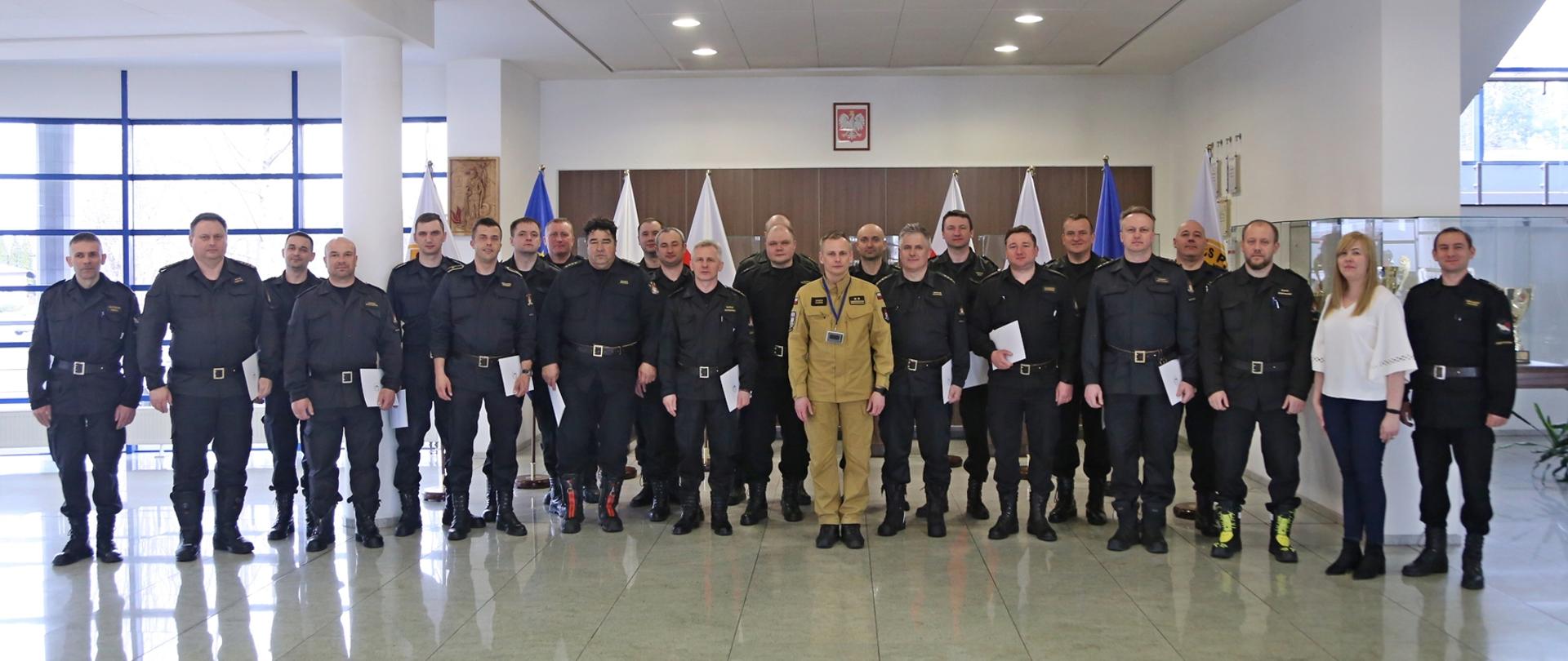 Grupowe zdjęcie uczestników szkolenia w towarzystwie Zastępcy Komendanta Centralnej Szkoły PSP oraz pracowników Szkoły sprawującymi nadzór nad szkoleniem