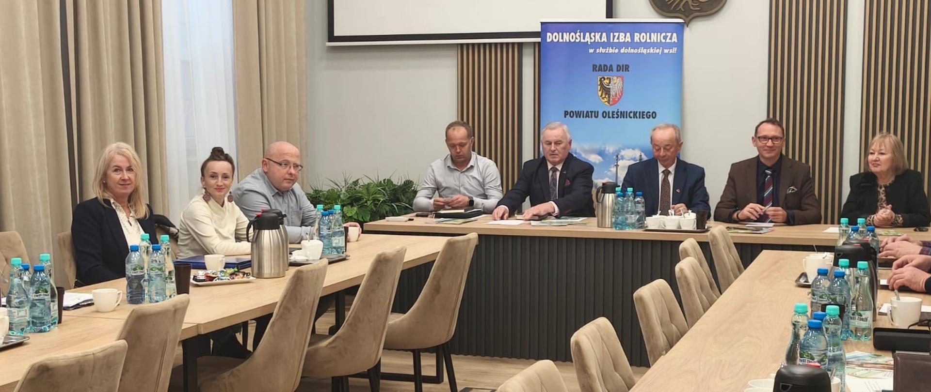 Uczestnicy spotkania siedzący w sali konferencyjnej. W tle baner Rady Powiatowej Dolnośląskiej Izby Rolniczej Powiatu Oleśnickiego