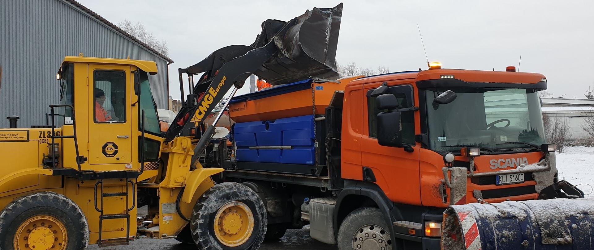 koparka Ładuje sól drogową na ciężarówkę z pługiem do odśnieżania 