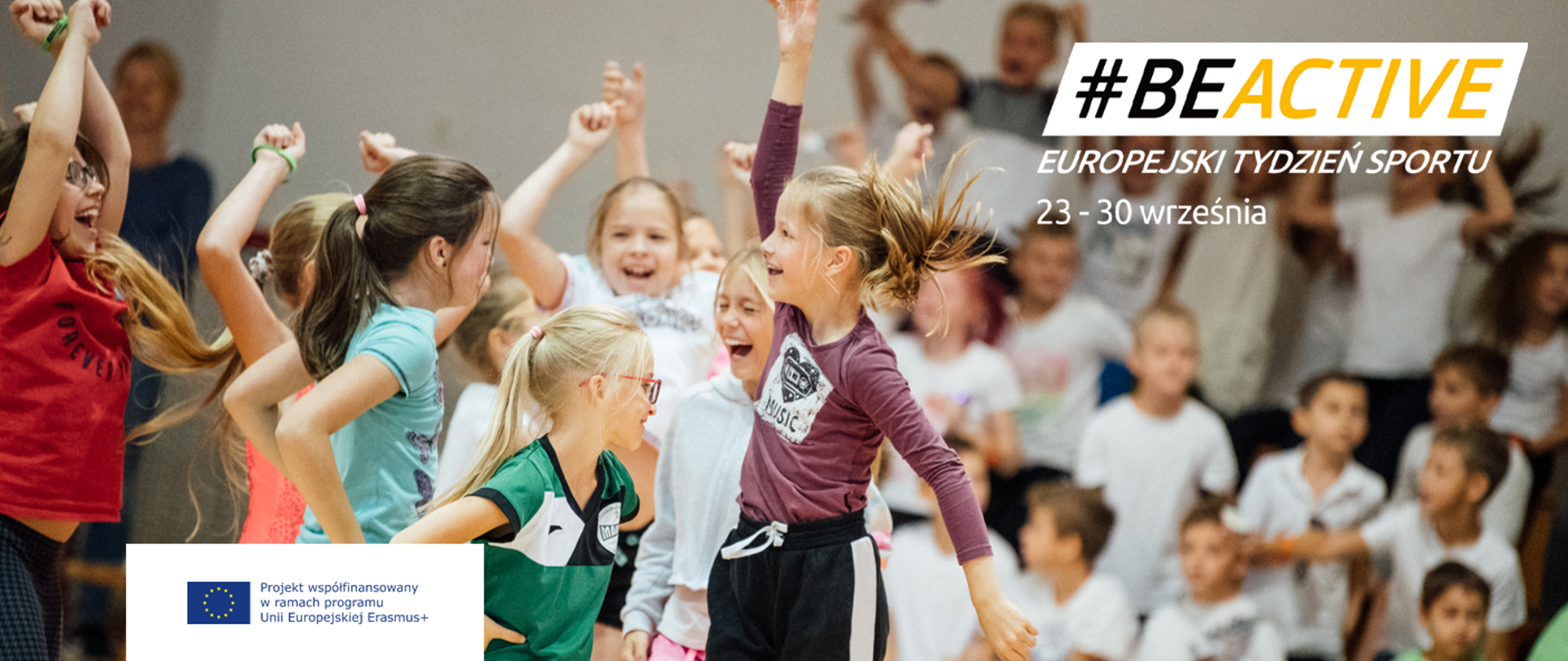 Grupa dzieci podskakuje. Na twarzach uśmiechy. Na pierwszym planie #BeActive Europejski Tydzień Sportu 23-30 Września.