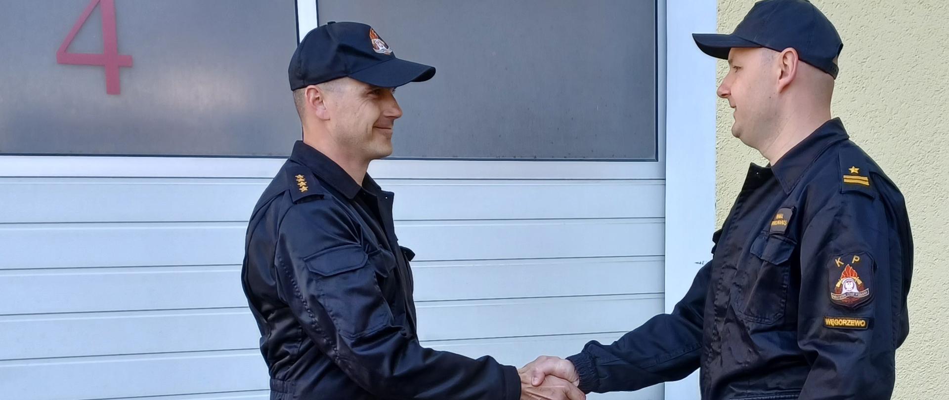 Na placu przed garażami Komendant wręcza decyzję powierzenia obowiązków Dowódcy JRG 