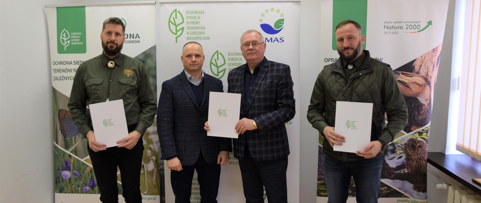 Trzech mężczyzn pozuje do zdjęcia, w rękach trzymają podpisane porozumienie.