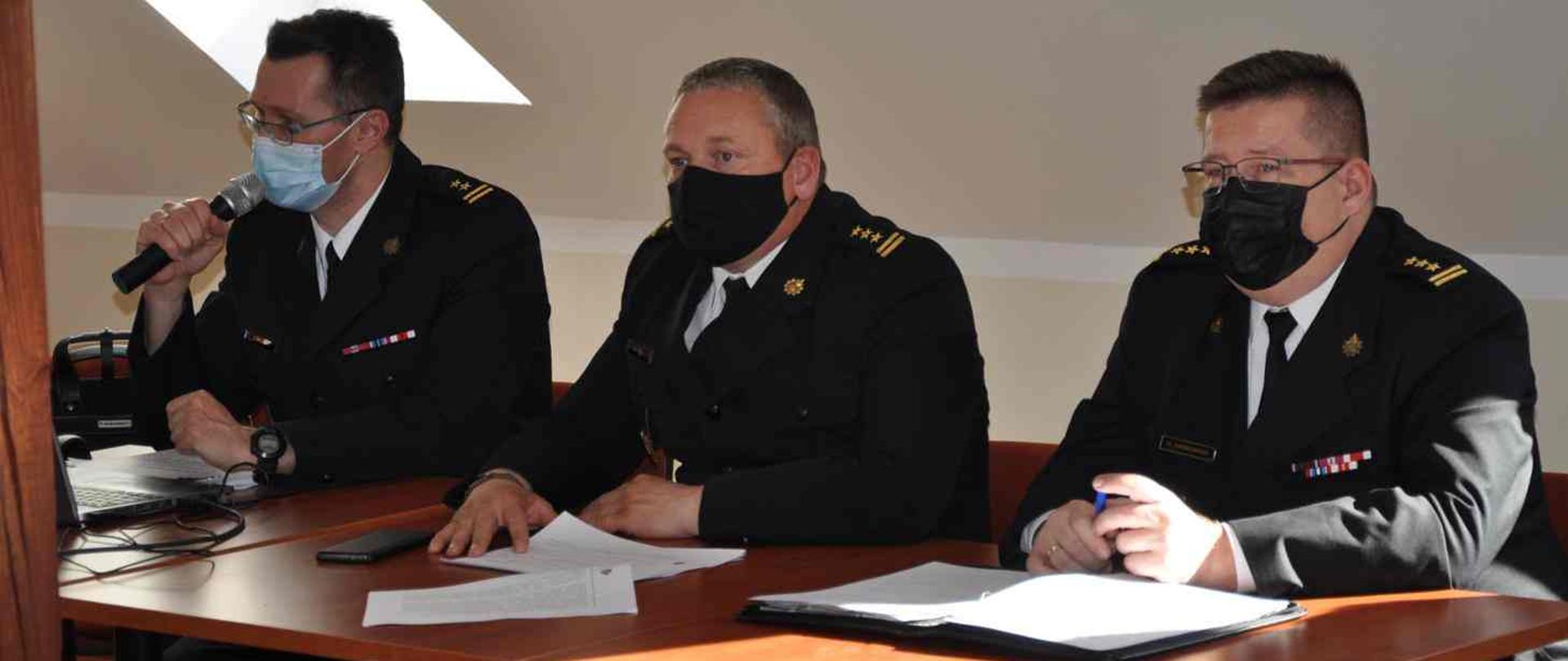 Strażacy siedzący przy stole i omawiający przepisy nowej ustawy.