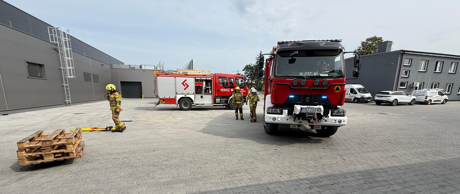 Wóz strażacki i strażacy stoją na kostce 