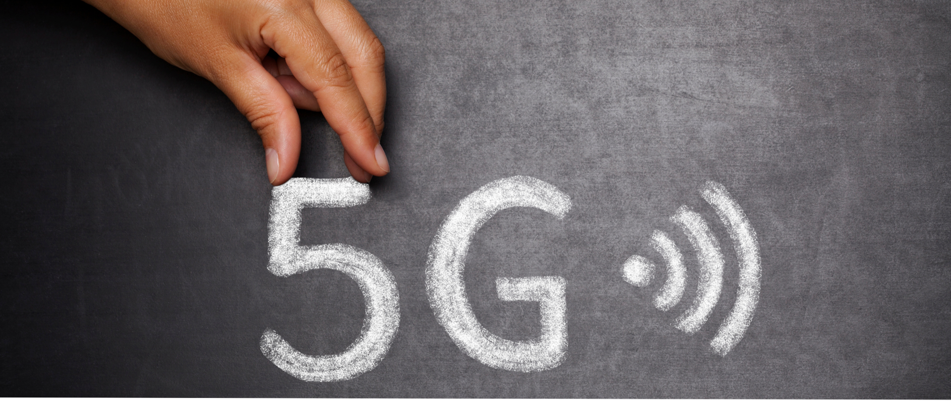 Dłoń męska oraz napis kredą na tablicy: 5G i znak graficzny, symbolizujący WiFi