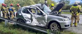 Uszkodzony samochód osobowy oraz strażacy