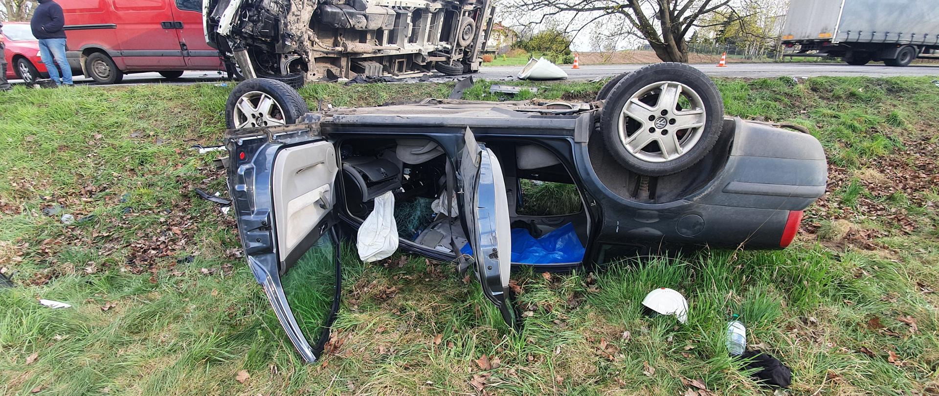 Auto osobowa na dachu poza jezdnią, auto ciężarowe przewrócone na bok