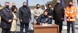 podpis wiceministra infrastruktury, w tle budowa drogi