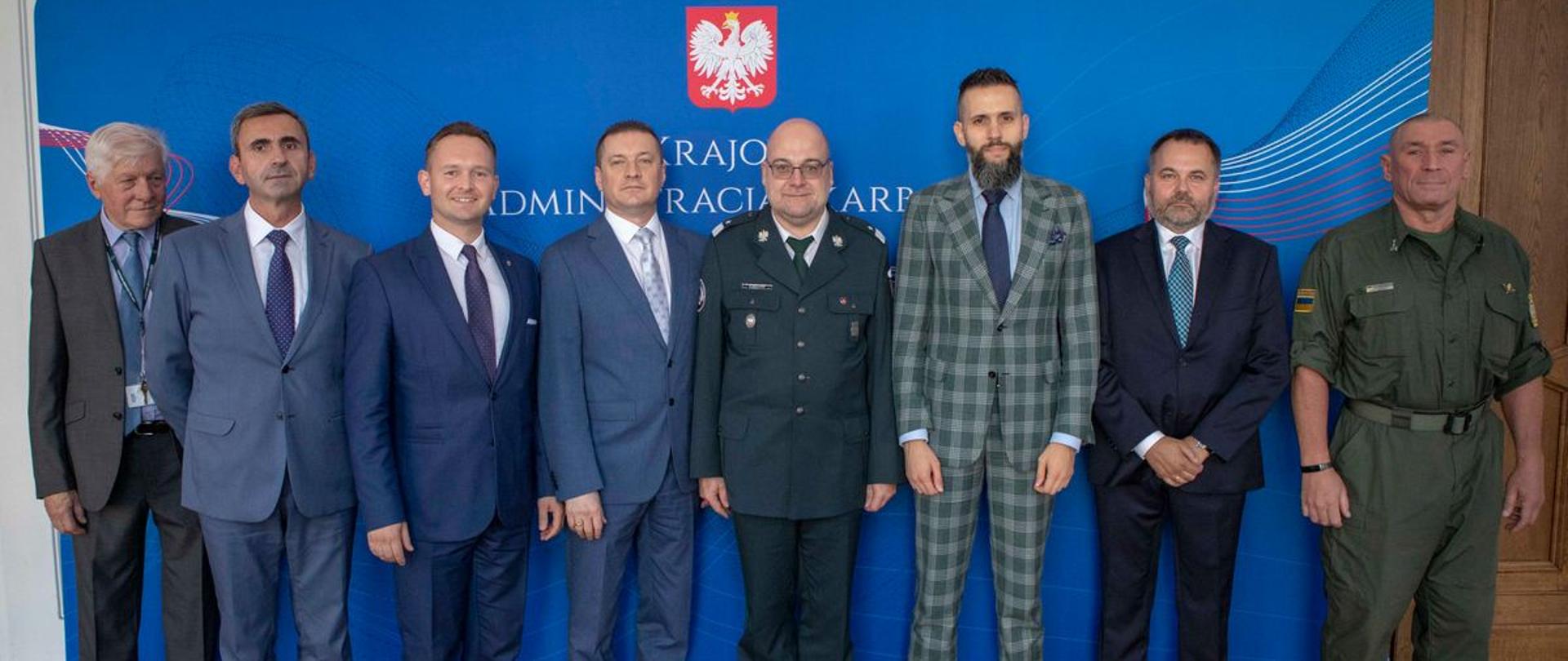 Szef KAS Piotr Walczak wraz z delegacją z Ukrainy na tle niebieskiej ścianki z napisem Krajowa Administracja Skarbowa