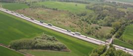 autostrada A4 widziana z lotu ptaka. Po prawej i lewej stronie autostrady widać lasy i pola. Na autostradzie sznur samochodów ciężarowych.