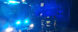 Strażacy stoją przed blokiem, w którym doszło do wybuchu gazu
