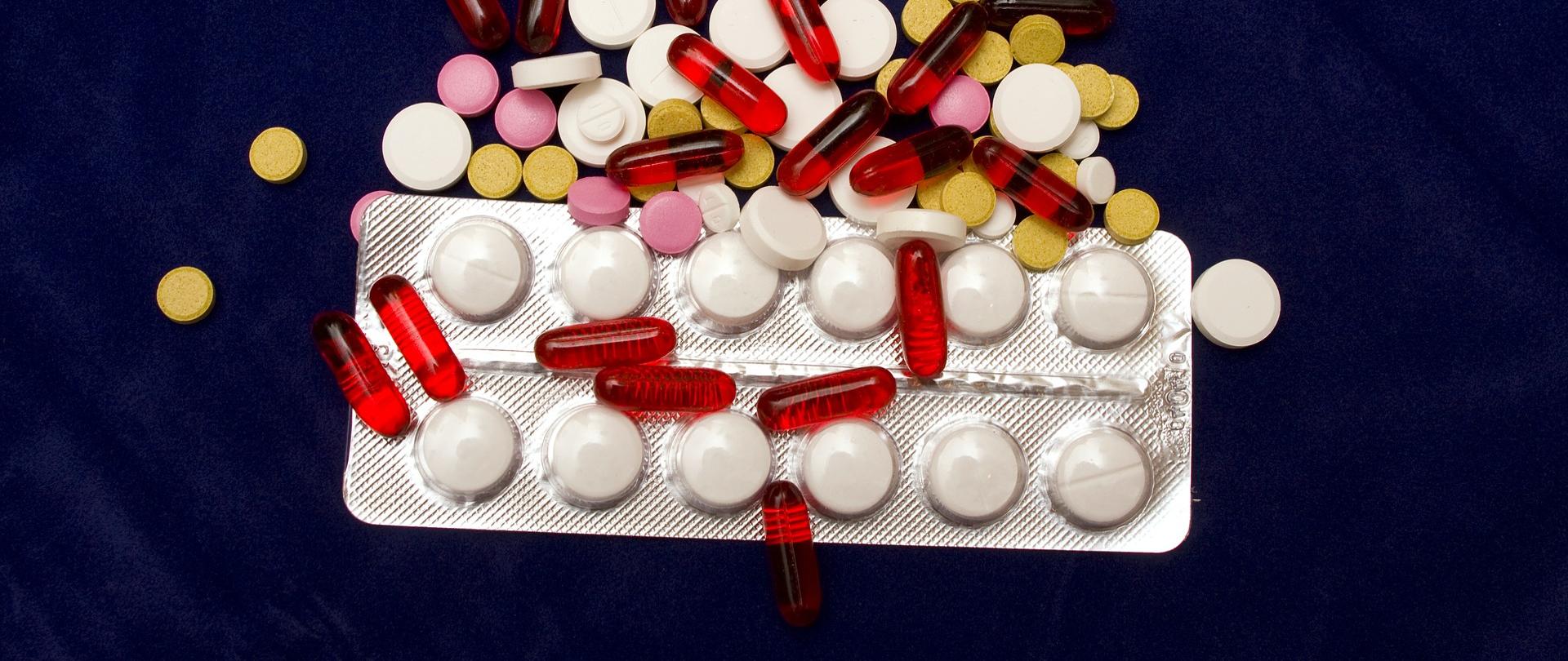 Kolorowe tabletki na granatowym tle.