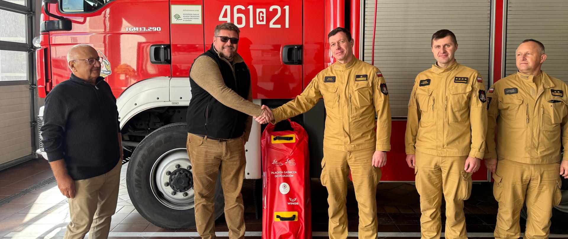 Przedstawiciele firmy przekazują funkcjonariuszom płachtę gaśniczą