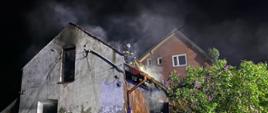 Strażacy prowadzą działania gaśnicze na dach budynku 