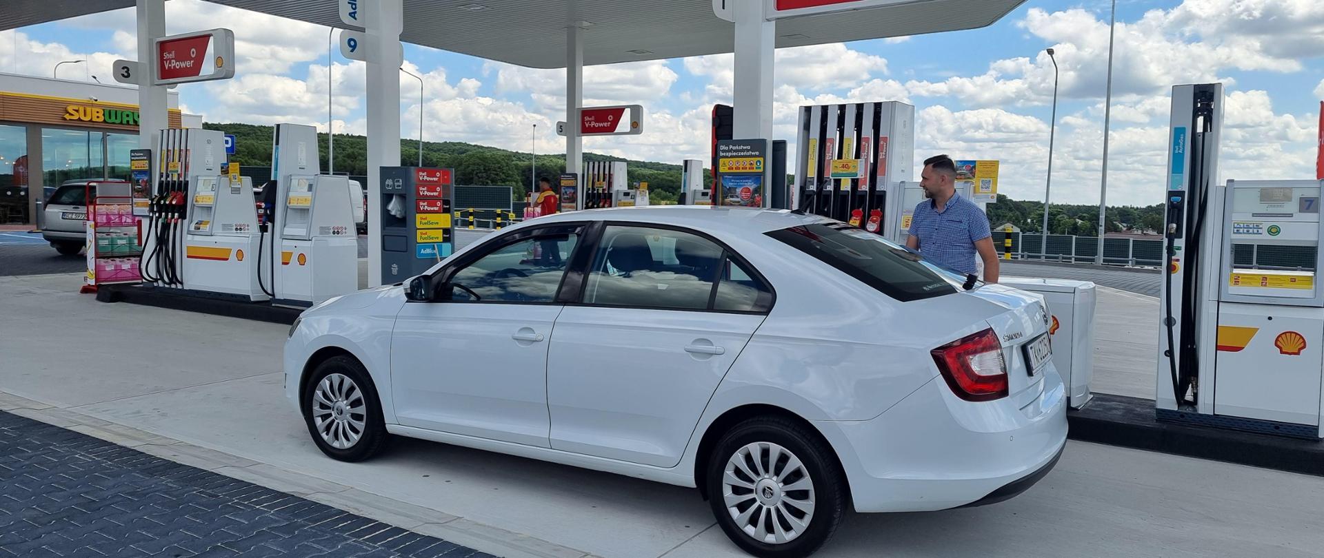 S7 MOP Szewce Wschód - na zdjęciu miejsce obsługi podróżnych, stacja paliw, dystrybutory, mężczyzna tankujący samochód osobowy, w oddali budynek stacji