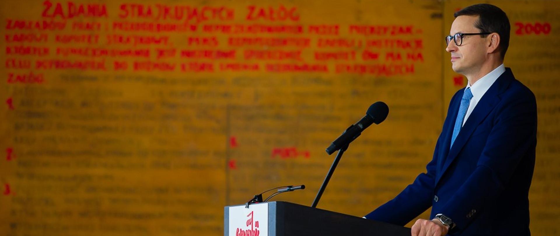 Premier stoi przy mównicy podczas przemówienia.